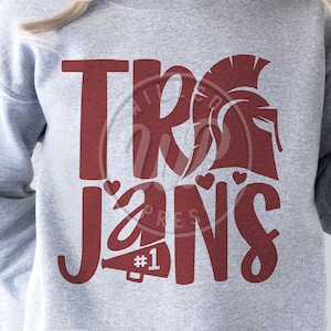 Könnte beinhalten: Ein graues Sweatshirt mit dem Schriftzug "Trojans" in roten Buchstaben. Der Text ist mit einem Herzen und einem Megaphon mit der Nummer "#1" darauf stilisiert. Über dem Wort "Trojans" befindet sich eine rote Silhouette eines trojanischen Kriegerhelms.