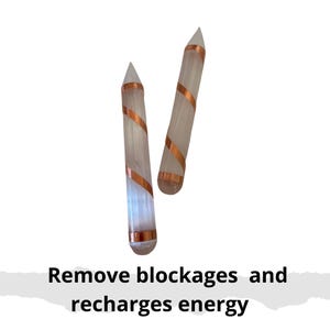 May include: Two clear, cylindrical crystal wands with copper wire spiraling around them. The wands have pointed tips and are displayed against a white background. Text at the bottom reads "Remove blockages and recharges energy."
