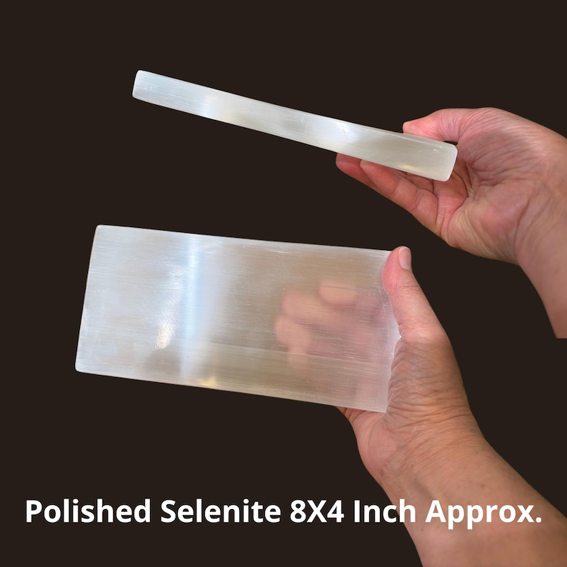 May include: A rectangular slab of polished white selenite with a translucent, fibrous appearance. The stone is shown from two angles, displaying its smooth, flat surface and thickness. The text Polished Selenite 8X4 Inch Approx. is visible.