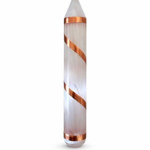 May include: A clear, elongated crystal with a pointed top, wrapped with copper-colored bands. The crystal is a light, translucent color, and the copper bands are spiraled around the body of the crystal.