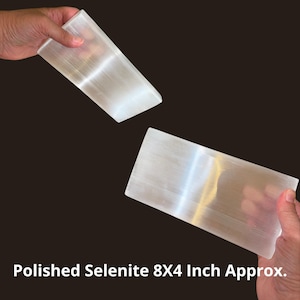 May include: Two rectangular blocks of translucent white polished selenite, each measuring approximately 8 by 4 inches. The stones have a smooth, fibrous texture with a reflective sheen, displayed against a dark background with the text Polished Selenite 8X4 Inch Approx.