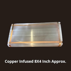 May include: A rectangular selenite slab featuring a translucent, fibrous white texture with metallic copper-colored bands wrapped around the perimeter. The text Copper Infused 8X4 Inch Approx. is printed in white at the bottom of the image.
