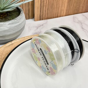 May include: Close-up of a spool of clear elastic string with a colorful label that reads "Crystal String Best Quality".