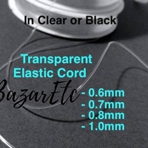 May include: A spool of clear or black transparent elastic cord in various sizes: 0.6mm, 0.7mm, 0.8mm, and 1.0mm. The cord is shown looped and coiled. The text "Transparent Elastic Cord" and "BazarEtc" are visible on the image.