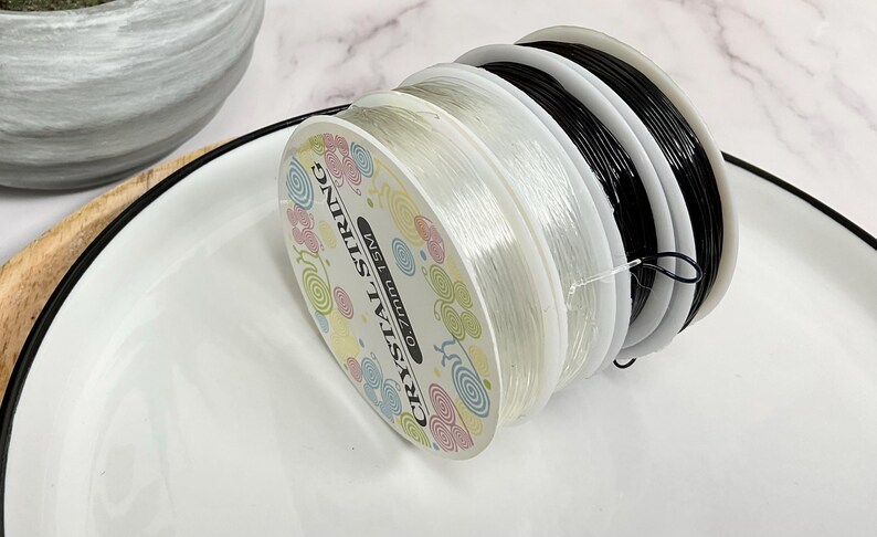 May include: A spool of clear elastic string with a label that reads "Crystal String 0.7mm 15M".
