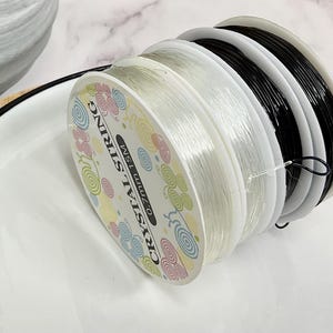 May include: A spool of clear elastic string with a label that reads "Crystal String 0.7mm 15M".