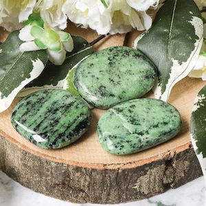 Pode incluir: Três pedras de jaspe zebra verde e preto polidas e lisas sobre uma superfície de madeira.