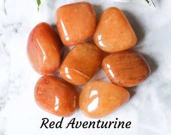 May include: Seven smooth, polished red aventurine tumbled stones. The stones are a deep reddish-orange color with a slight shimmer.
