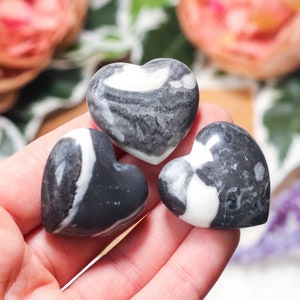 Peut inclure: Trois pierres en forme de c&oelig;ur noires et blanches. Les pierres ont un motif tourbillonnant de noir et de blanc.