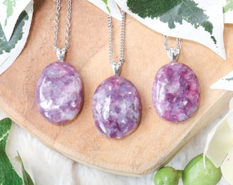 May include: Three silver chain necklaces with oval-shaped lepidolite pendants. The pendants are a mix of purple, pink, and white.