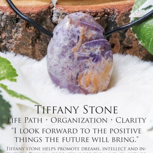 Puede incluir: Colgante de piedra Tiffany con cord&oacute;n negro. La piedra muestra una mezcla de tonos morados y anaranjados. El texto en la imagen dice "Tiffany Stone" y "I look forward to the positive things the future will bring."