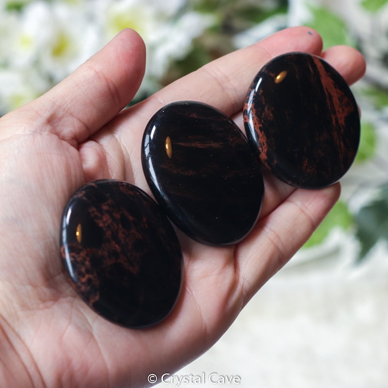 May include: Three black and red jasper palm stones. The stones are smooth and polished, with a natural, organic look.
