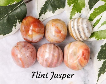 May include: Six smooth, polished Flint Jasper stones in various shades of pink, orange, and white. The stones are arranged in a circle on a white surface.