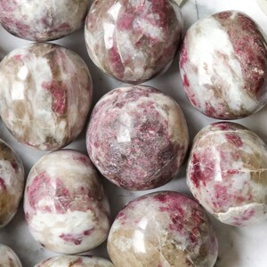 May include: A collection of tumbled pink and white stones with a smooth, polished finish. The stones have a natural, organic look and feel.