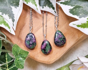 May include: Three silver necklaces with green and pink gemstone pendants. The pendants are teardrop shaped and have a natural, rough texture.