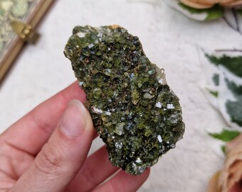 May include: A cluster of green and clear crystals, with a rough, natural texture. The crystals are clustered together in a dense formation, creating a unique and interesting piece.