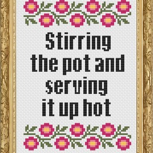 May include: Cross-stitch pattern with a white background and black text that reads "Stirring the pot and serving it up hot". The text is framed by a border of pink flowers with yellow centres and green leaves.