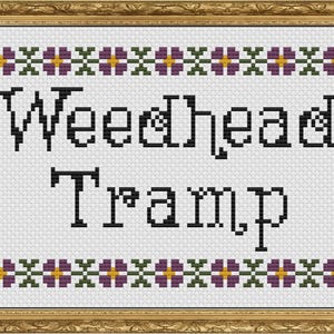 May include: Cross-stitch art piece in a gold frame. The white background features the words "Weedhead Tramp" in black, stylized lettering. Floral border designs in purple, green, and yellow adorn the top and bottom.