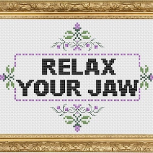 May include: Cross-stitch pattern with a white background and purple and green floral accents. The pattern reads "Relax Your Jaw" in black text.