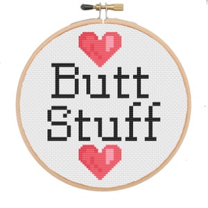 Op de afbeelding: Een witte borduurring met een zwart-wit borduurwerkontwerp met de tekst "Butt Stuff" met een rood hart erboven en eronder.