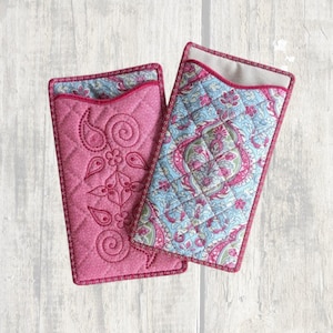 May include: Two rectangular quilted fabric pouches. One pouch is solid pink with a stitched paisley and floral pattern. The second pouch features a light blue and pink paisley floral print with a diamond-stitched quilted texture and pink trim.