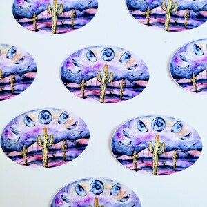 May include: Oval stickers featuring a watercolor design of a desert landscape with cacti, mountains, and a night sky with moon phases. The color palette includes purple, blue, and yellow hues. The stickers are arranged on a white background.