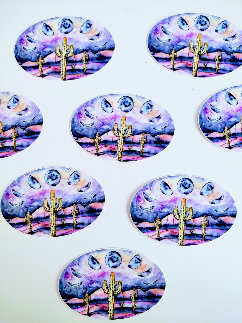 May include: Oval stickers featuring a watercolor design of a desert landscape with cacti, mountains, and a night sky with moon phases. The color palette includes purple, blue, and yellow hues. The stickers are arranged on a white background.