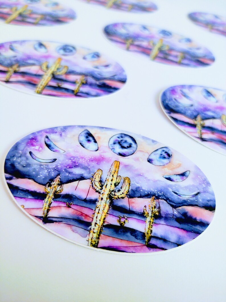 May include: Oval stickers featuring a watercolor desert scene with cacti, a starry sky, and moon phases. The color palette includes purple, pink, and yellow. The stickers are on a white background.