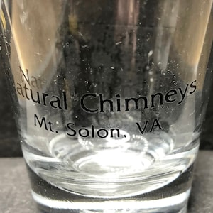 May include: A clear glass shot glass with the text "Natural Chimneys Mt. Solon, VA" printed on the side.