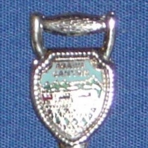 Puede incluir: Una cuchara de recuerdo de plata con un diseño de esmalte azul y blanco que representa un paisaje con las palabras "Nueva Escocia" en ella.