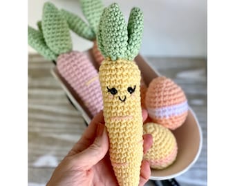 May include: A crocheted carrot toy with a smiling face and green leaves. The carrot is yellow and has pink stripes. The toy is sitting in a basket with other crocheted items.