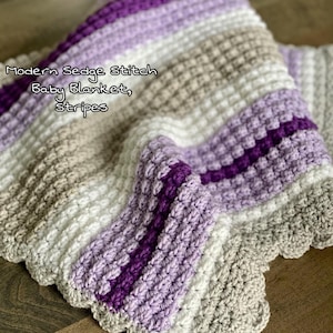 May include: A crocheted baby blanket with a striped pattern in shades of purple, white, and gray. The blanket features a textured sedge stitch design and the text "Modern Sedge Stitch Baby Blanket, Stripes".