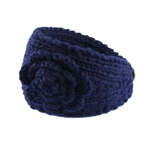 Puede incluir: Una diadema de punto azul marino con un gran detalle de flor. La diadema está hecha de un material suave y cómodo y es perfecta para mantener las orejas calientes en invierno.