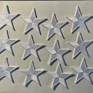 May include: Twelve white felt star-shaped patches. Each star has five points and a raised, textured surface.