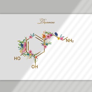 May include: A floral illustration of the chemical structure of dopamine. The molecule is outlined in gold and decorated with watercolor flowers in shades of pink, yellow, and blue. The text "Dopamine" is written in gold script at the top of the image.