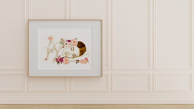 May include: A watercolour painting of a woman with a floral crown sleeping on a bed of flowers. The painting is framed in a light wood frame and is hanging on a white wall.
