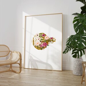 May include: A gold circle with pink and white flowers and green leaves. The flowers are arranged in a circular pattern around the gold circle. The background is white.