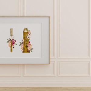 May include: A framed print with a gold toothbrush and a gold tube of toothpaste, both decorated with pink and white flowers.