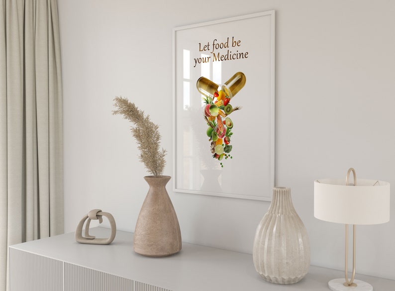 May include: A white framed print with the text "Let food be your medicine" and a graphic of a capsule filled with various fruits and vegetables.