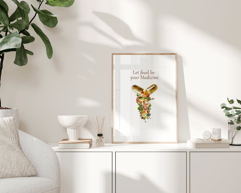 May include: A framed print with a white background and the text "Let food be your medicine". The image shows two gold capsules filled with colorful fruits and vegetables.