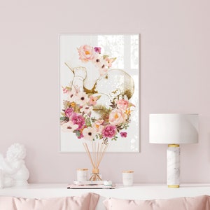 May include: A white framed print with a gold outline of a baby in a floral wreath. The flowers are pink, white, and cream.