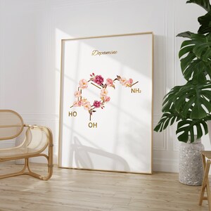 Pode incluir: Um cartaz branco com a palavra "Dopamina" em letras douradas. A estrutura qu&iacute;mica da dopamina &eacute; representada por flores cor-de-rosa e brancas.