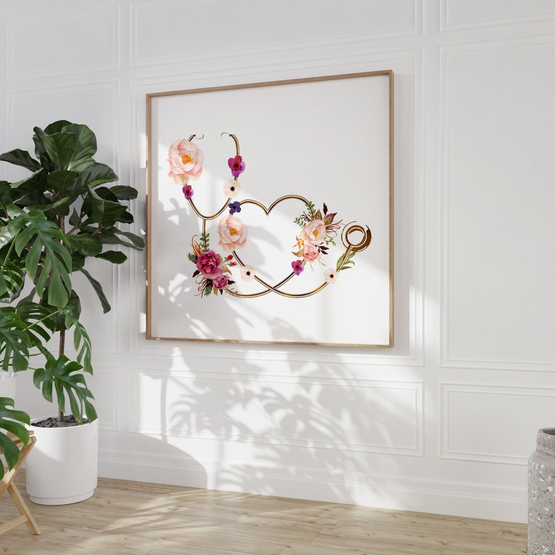May include: A framed print of a gold stethoscope with pink, white, and purple flowers arranged in the shape of a heart. The background is white.