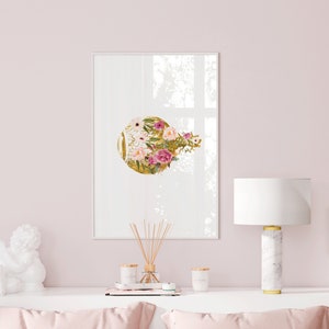 May include: A framed print with a gold circle and pink and white flowers on a white background. The print is hanging on a pink wall above a white table with a white ceramic angel figurine, a diffuser, and two candles.