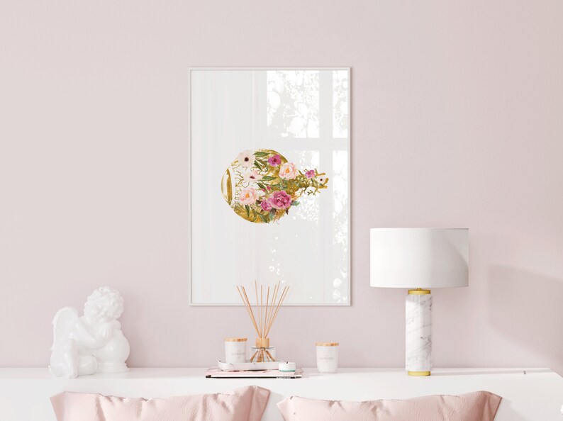 May include: A framed print with a gold circle and pink and white flowers on a white background. The print is hanging on a pink wall above a white table with a white ceramic angel figurine, a diffuser, and two candles.