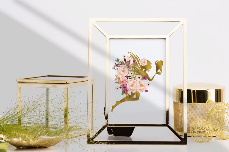May include: A gold picture frame with a white background and a gold silhouette of a fairy holding a tooth. The fairy is surrounded by pink and purple flowers.