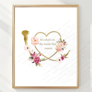 Puede incluir: Una impresión digital enmarcada con un contorno de corazón dorado rodeado de arreglos florales rosas y rojo oscuro. El texto dentro del corazón dice, It's what's on the inside that counts. Un corazón anatómico dorado está a la izquierda.
