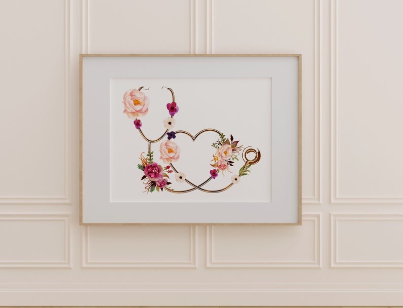 May include: A gold stethoscope with a heart shape formed by the tubing, decorated with pink, white, and purple flowers. The stethoscope is framed in a white frame with a wood border.