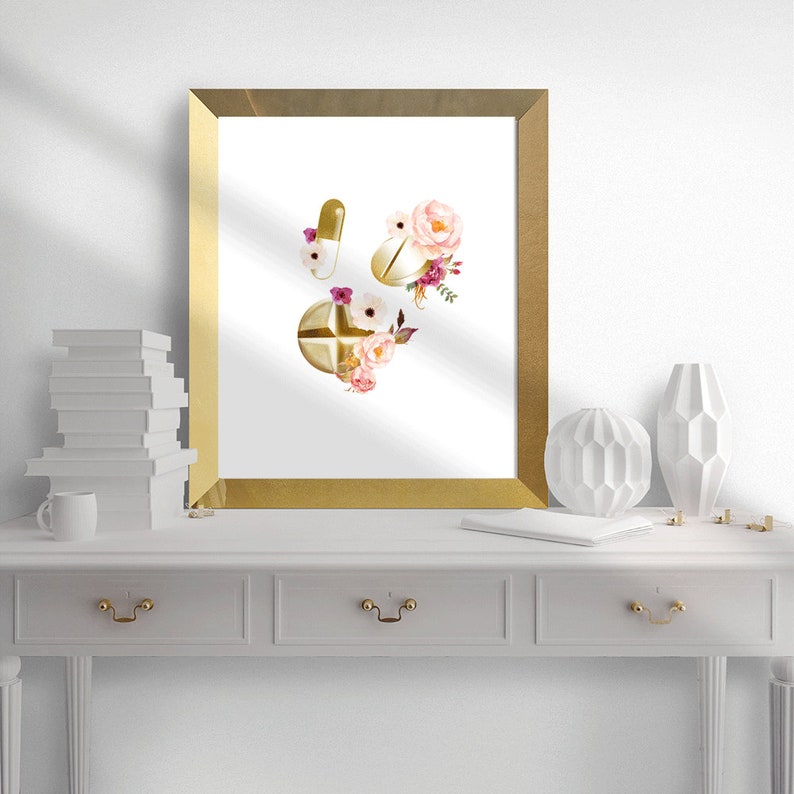 May include: A gold framed print with a watercolor illustration of gold pills and pink and white flowers.