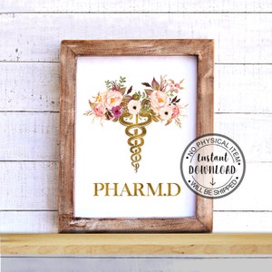 May include: A printable digital download of a gold medical caduceus symbol with pink and white floral accents. The text "PHARM.D." is below the symbol. The text "NO PHYSICAL ITEM. Instant DOWNLOAD. WILL BE SHIPPED" is in a circle around the image.
